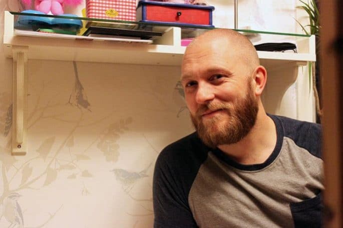 Pappa Conny sitter mot en vägg och ser glad ut