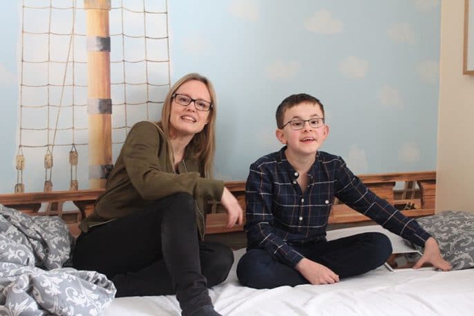 Susanne och Gustav sitter i Gustavs säng och ser glada ut