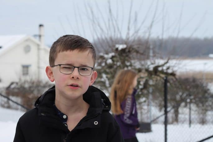Gustav i förgrunden och Freja suddigt i bakgrunden i en snöig utomhusmiljö