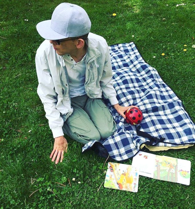 Zandras bror på en picnickfilt på en grön gräsmatta