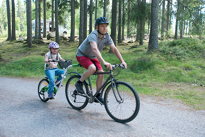Malin och Matti cyklar på en påhängscykel på en camping
