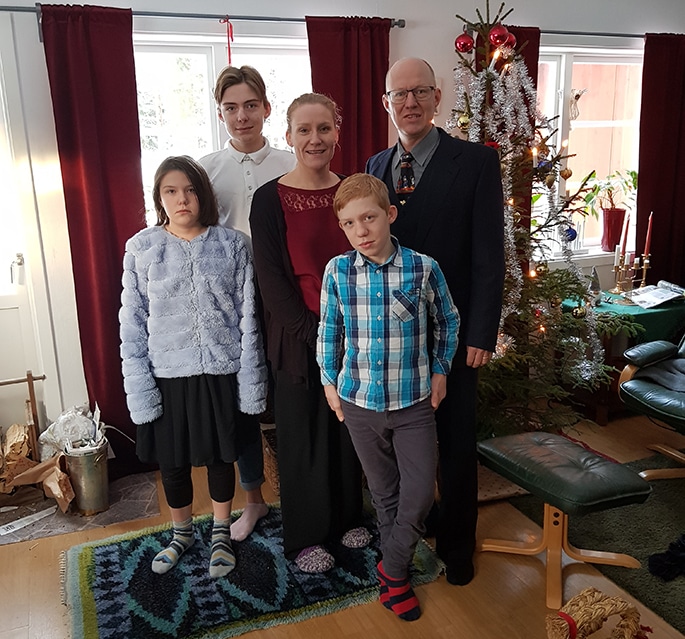Otto and his family standing in front of a Christmas tree